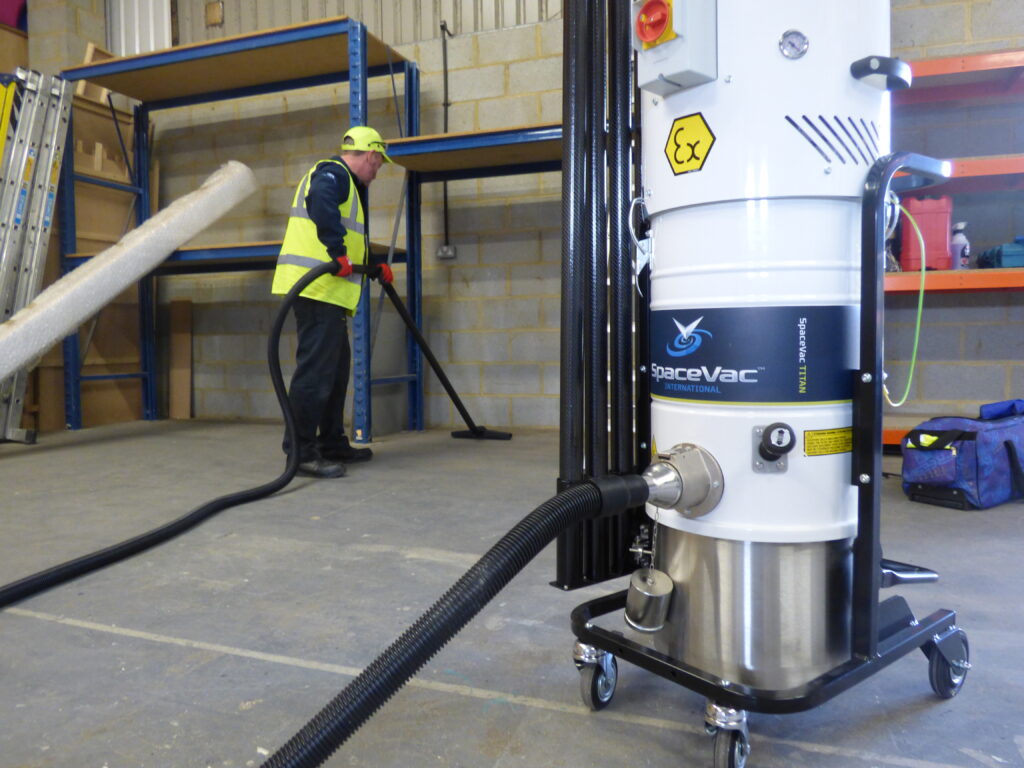 ATEX-rated vacuum unit with a high-reach pole in a woodworking shop, part of wood dust extraction and cleanup