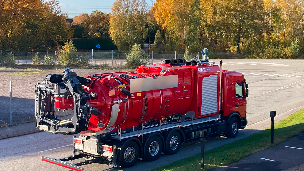 Red heavy-duty vacuum truck parked on a paved industrial site, the kind of unit used for crusher fines recovery