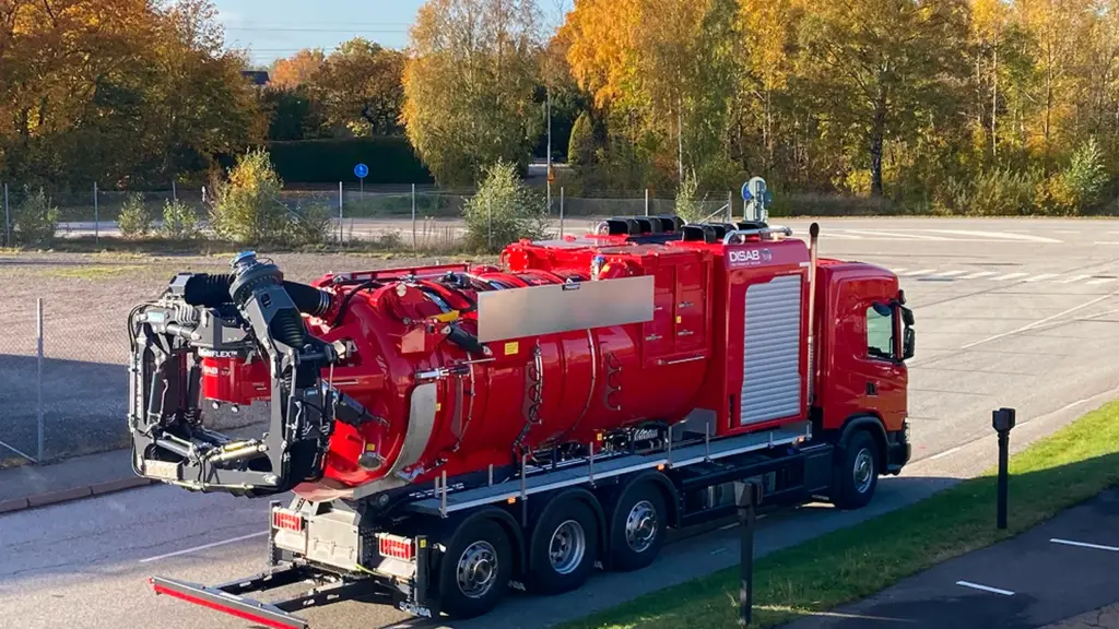 Red DISAB vacuum truck on a paved site, the kind of bulk vacuum loader used for cement plant material recovery