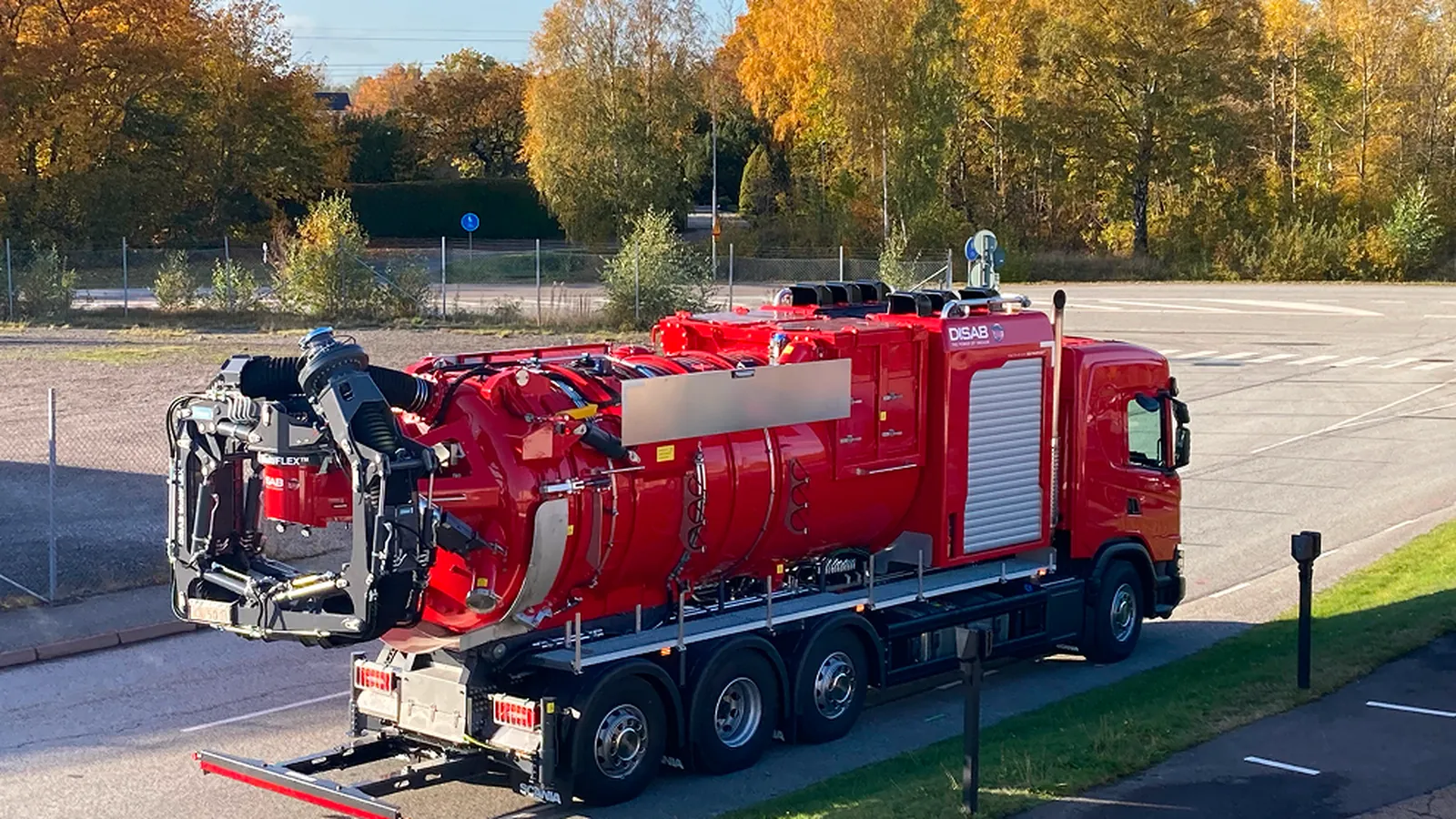 Red DISAB vacuum truck on a paved site, the kind of bulk vacuum loader used for cement plant material recovery