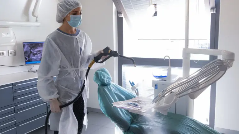 Operator in a protective gown using dry steam cleaning on equipment, a method evaluated for pharmaceutical equipment
