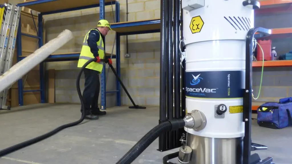 ATEX-rated vacuum unit with a high-reach pole in a woodworking shop, illustrating wood dust extraction and cleanup